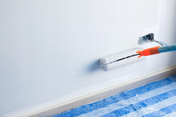 painter man with paint roller brush painting the wall.