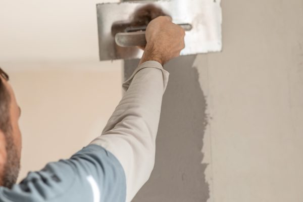 The man master plasters the wall, makes repairs in the apartment