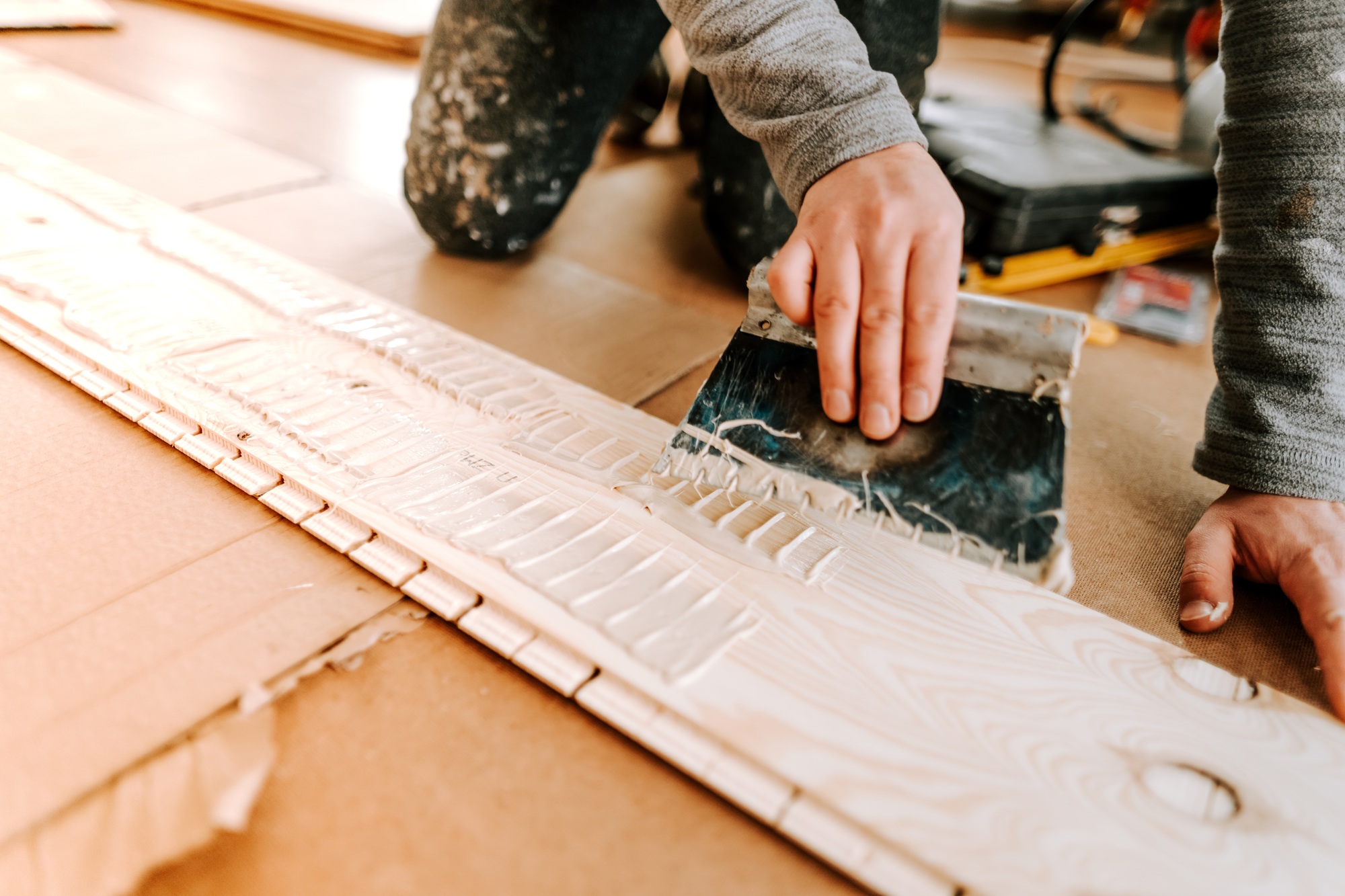 Worker laying and gluing parquet flooring