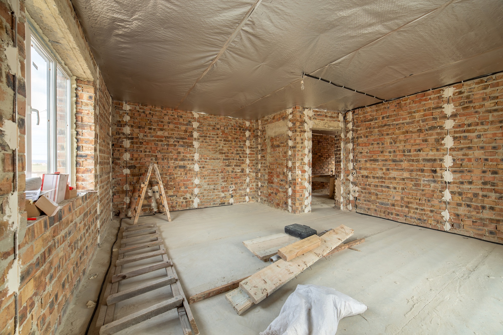 Interior of unfinished brick house with concrete floor and bare walls ready for plastering